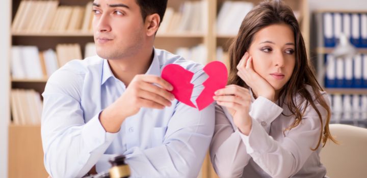 A man and woman holding a broken heart, hiring a Mutual Divorce Lawyer in Delhi.